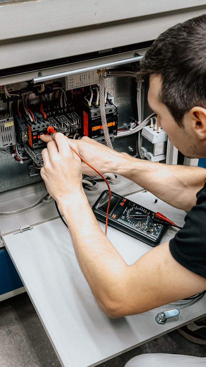 hero-img-02 An electrician uses a multimeter to test and diagnose connections in an open electrical panel.
