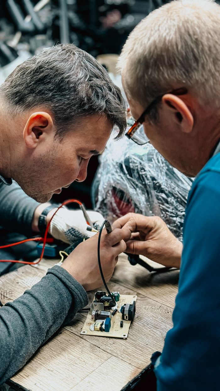 gallery-3 Focused technicians meticulously repair a circuit board in a workshop.