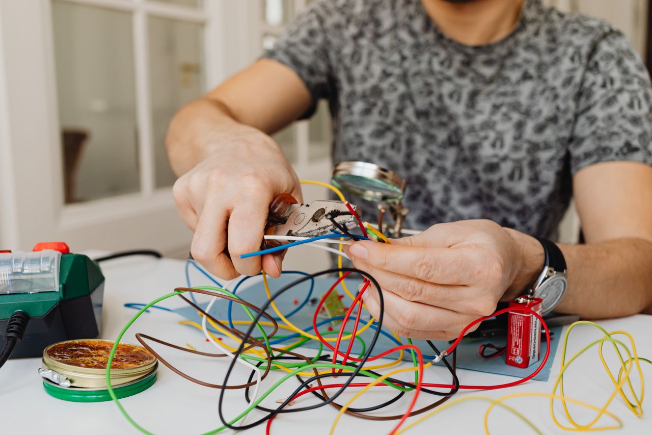 services-02 Person using pliers to cut through colorful electrical wires, showcasing DIY electronics work.